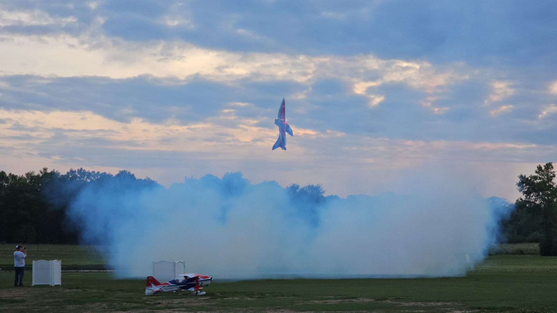 RC airplane climbing above smoke at the flying field