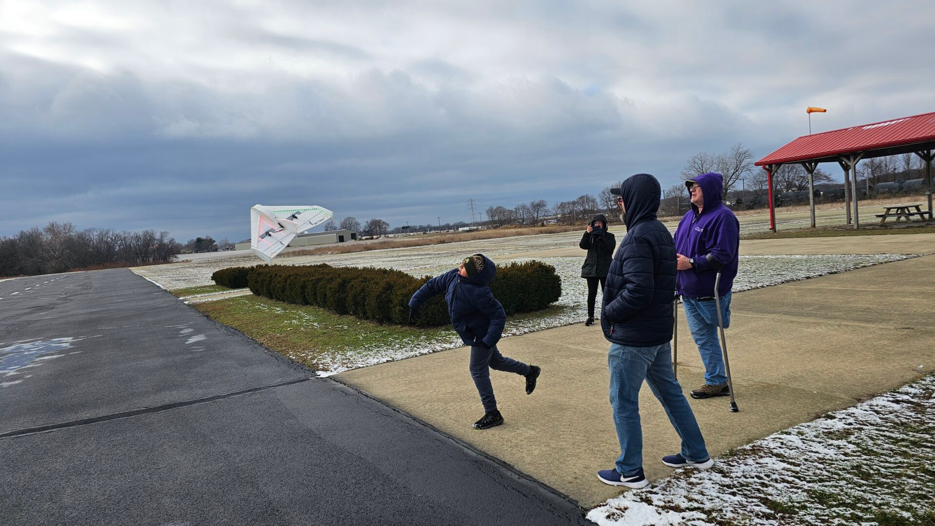 Friends flying a foam RC airplane together on a cold winter day