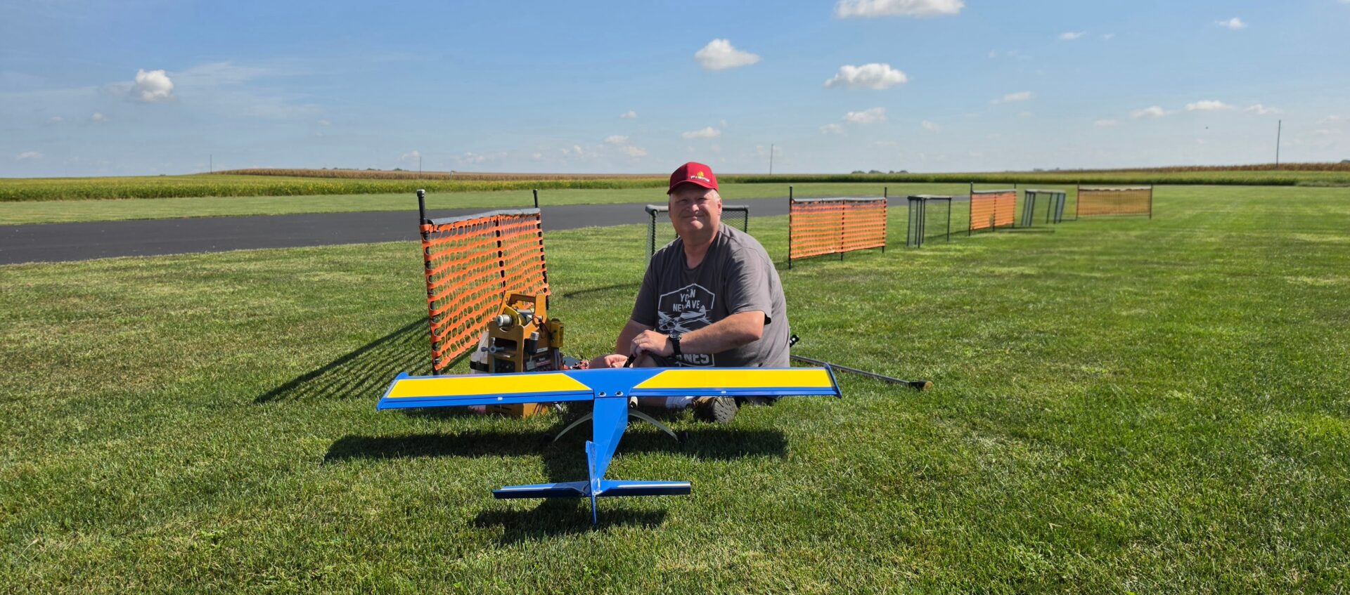 Modeler with a blue and yellow RC airplane at the flying field