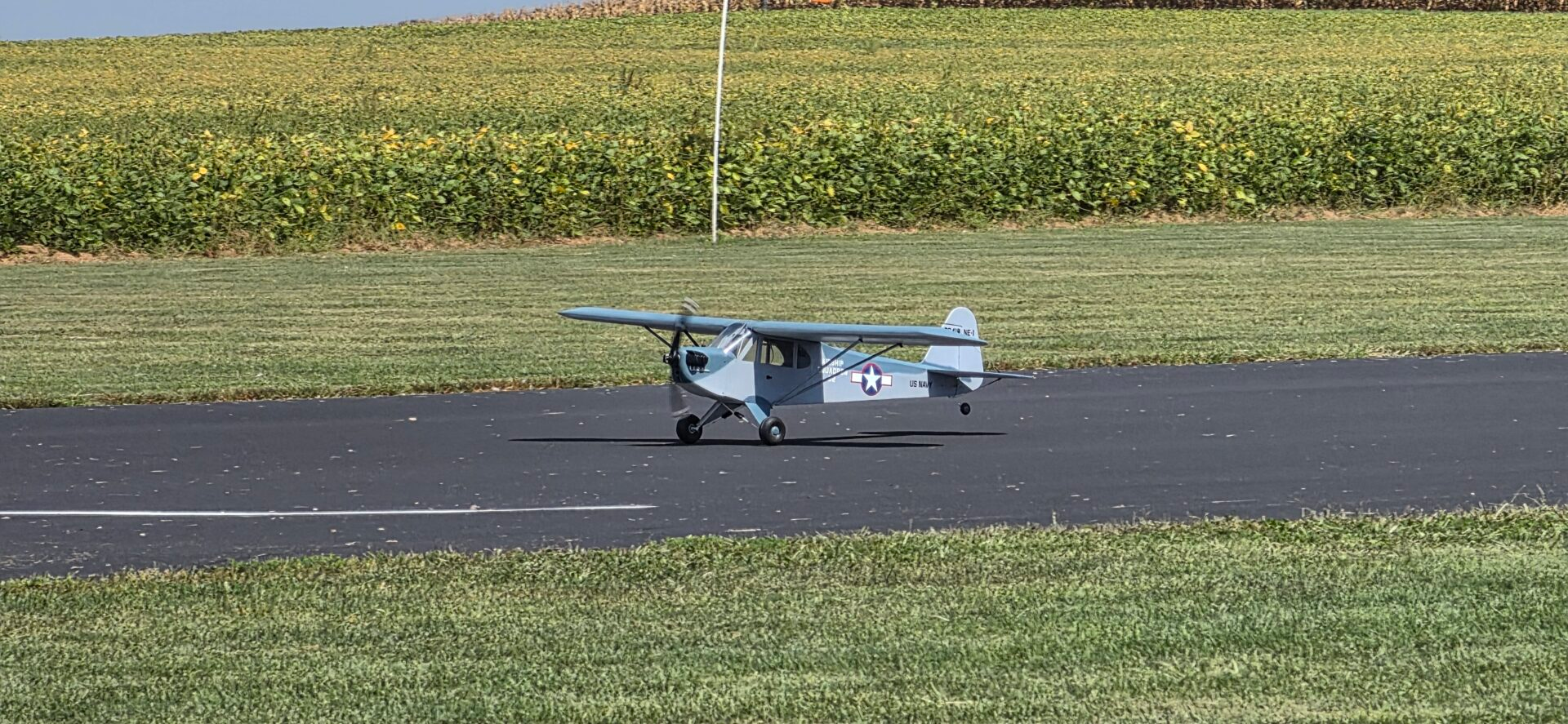 Gray RC airplane on a paved runway at the flying field